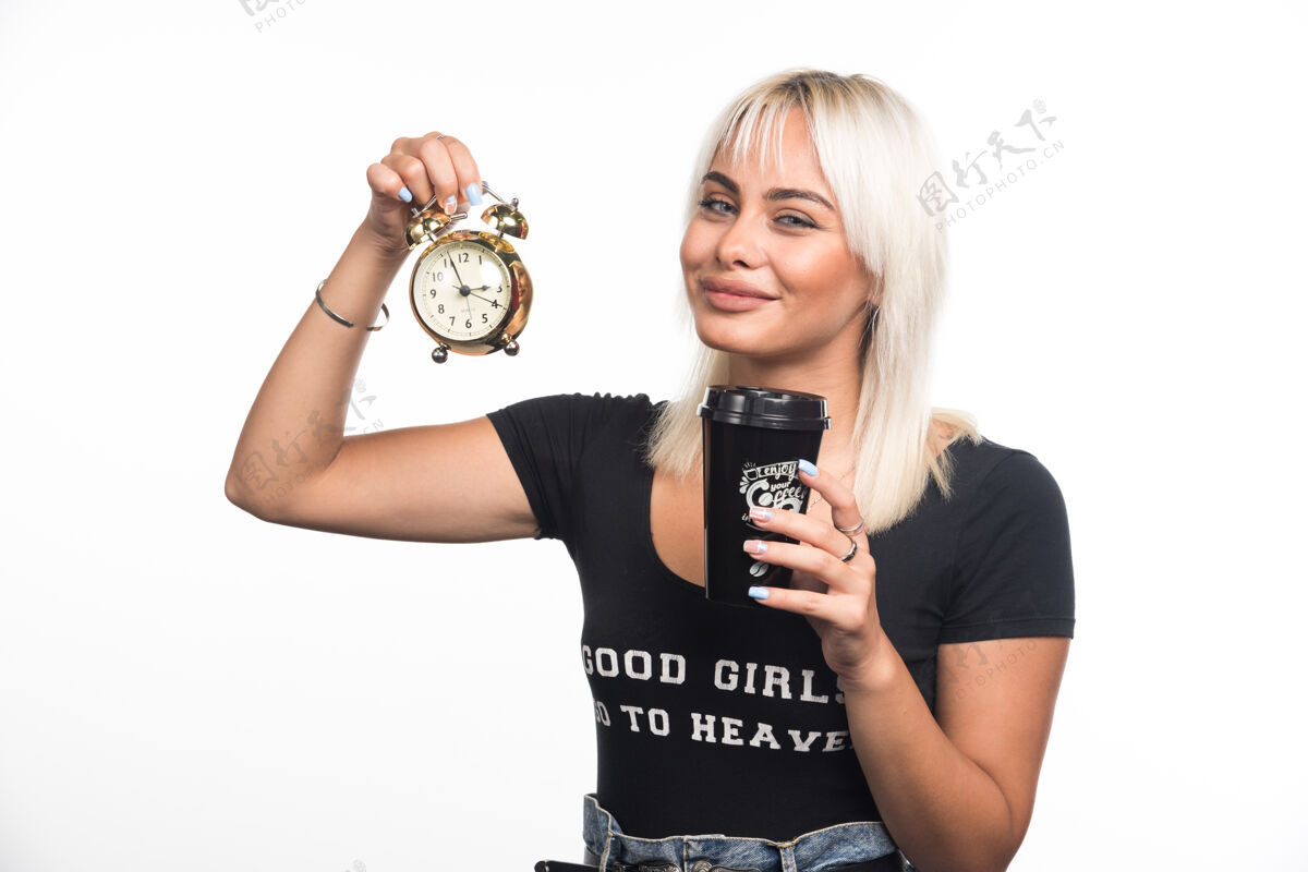 杯子在白墙上拿着钟和咖啡杯的年轻女人女人姿势肖像