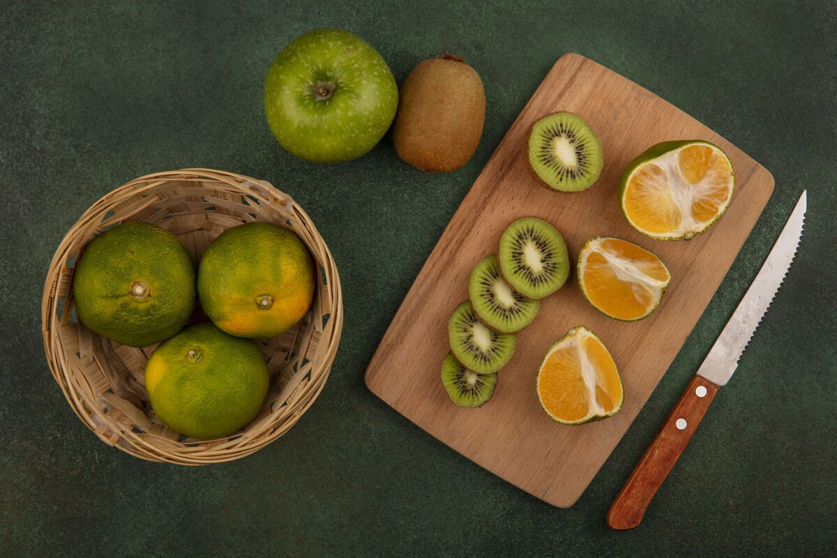 篮子俯瞰篮子里的橘子和苹果切肉板上的猕猴桃片切片切新鲜