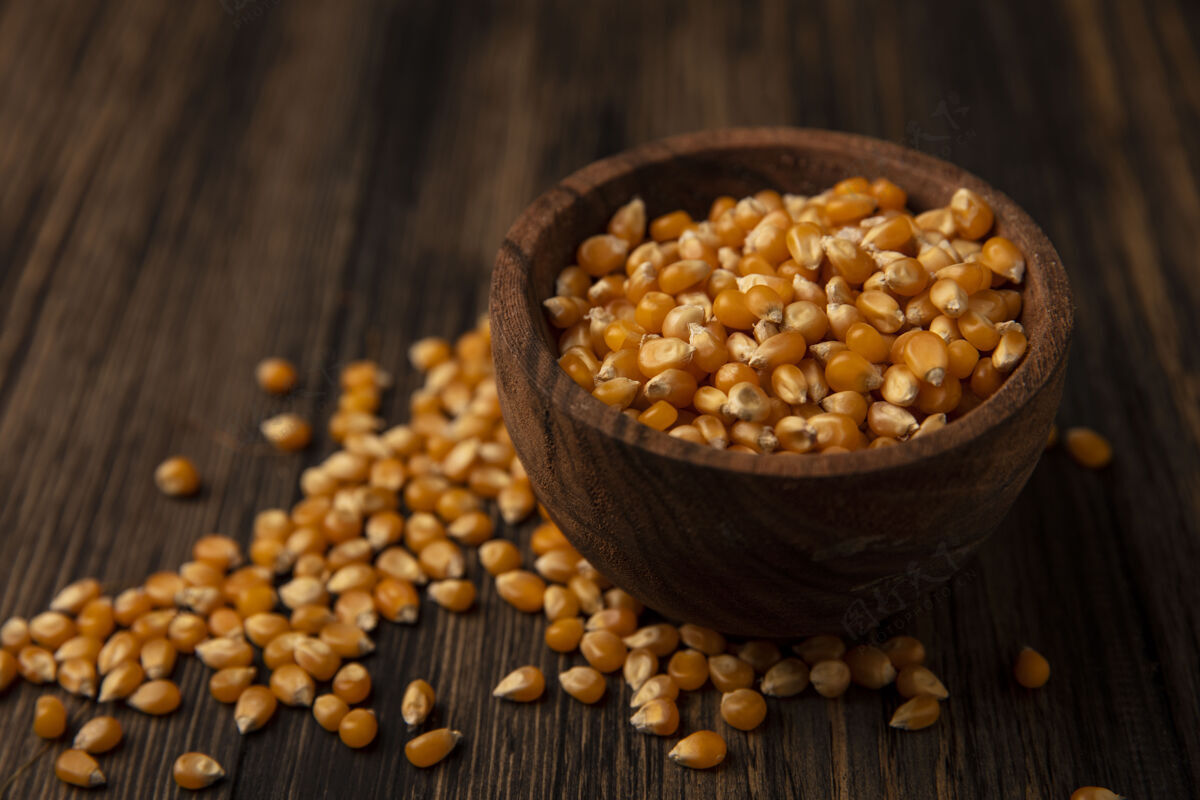 顶部黄色玉米粒放在木碗上的俯视图 玉米粒被隔离在木桌上有机谷物玉米