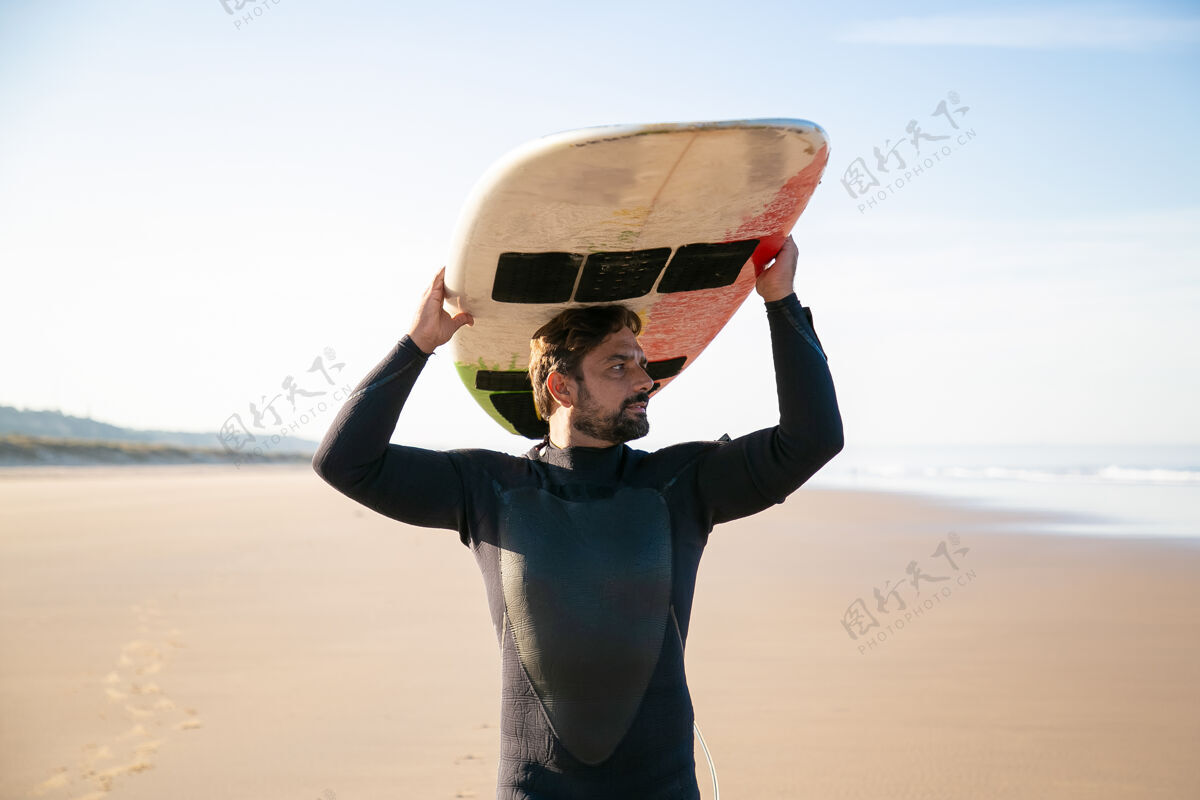旅游垂头丧气的男冲浪者 头上举着冲浪板 望着大海运动黑发自然