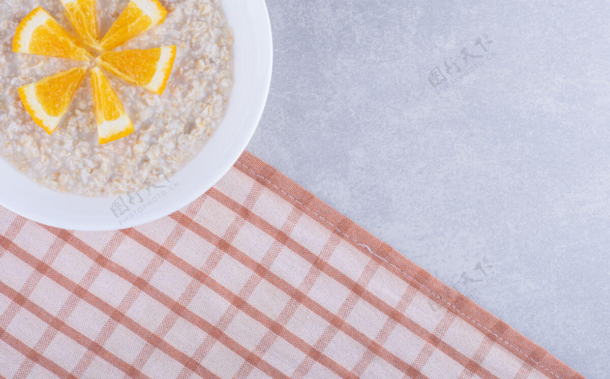 毛巾一盘燕麦片 上面放着橘子片 放在大理石表面橘子健康拼盘