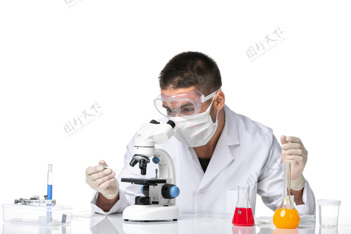 健康前视图：男医生穿着白色医疗服 戴着面罩 在白色空间使用显微镜套装医学视图