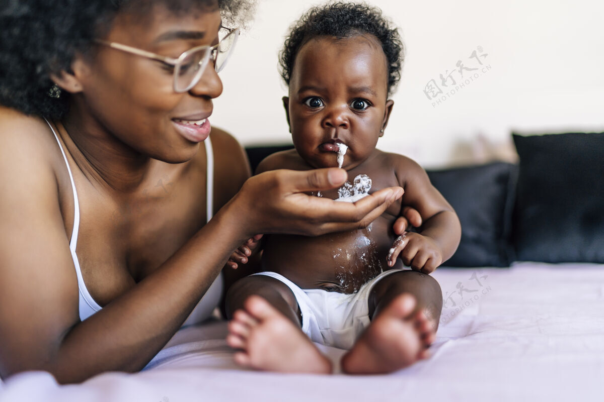 健康可爱的非洲裔美国宝宝在妈妈手里吐牛奶小食物孩子