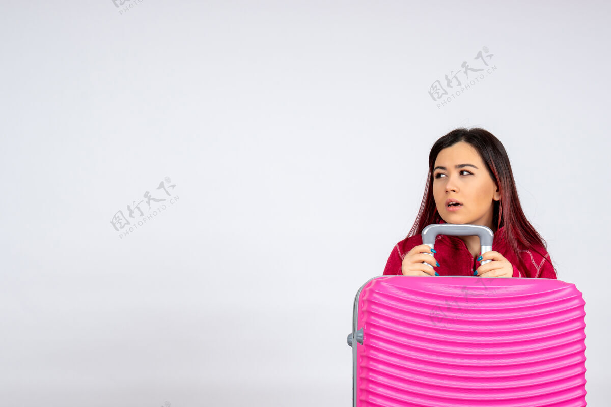漂亮前视年轻女性带着粉色包在白墙上的彩色情感度假航程飞行旅行女性风景微笑年轻的女性