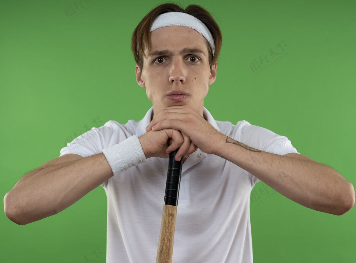 穿自信的年轻人戴着头带 手腕上拿着棒球棒 隔离在绿色的墙上运动自信棒球