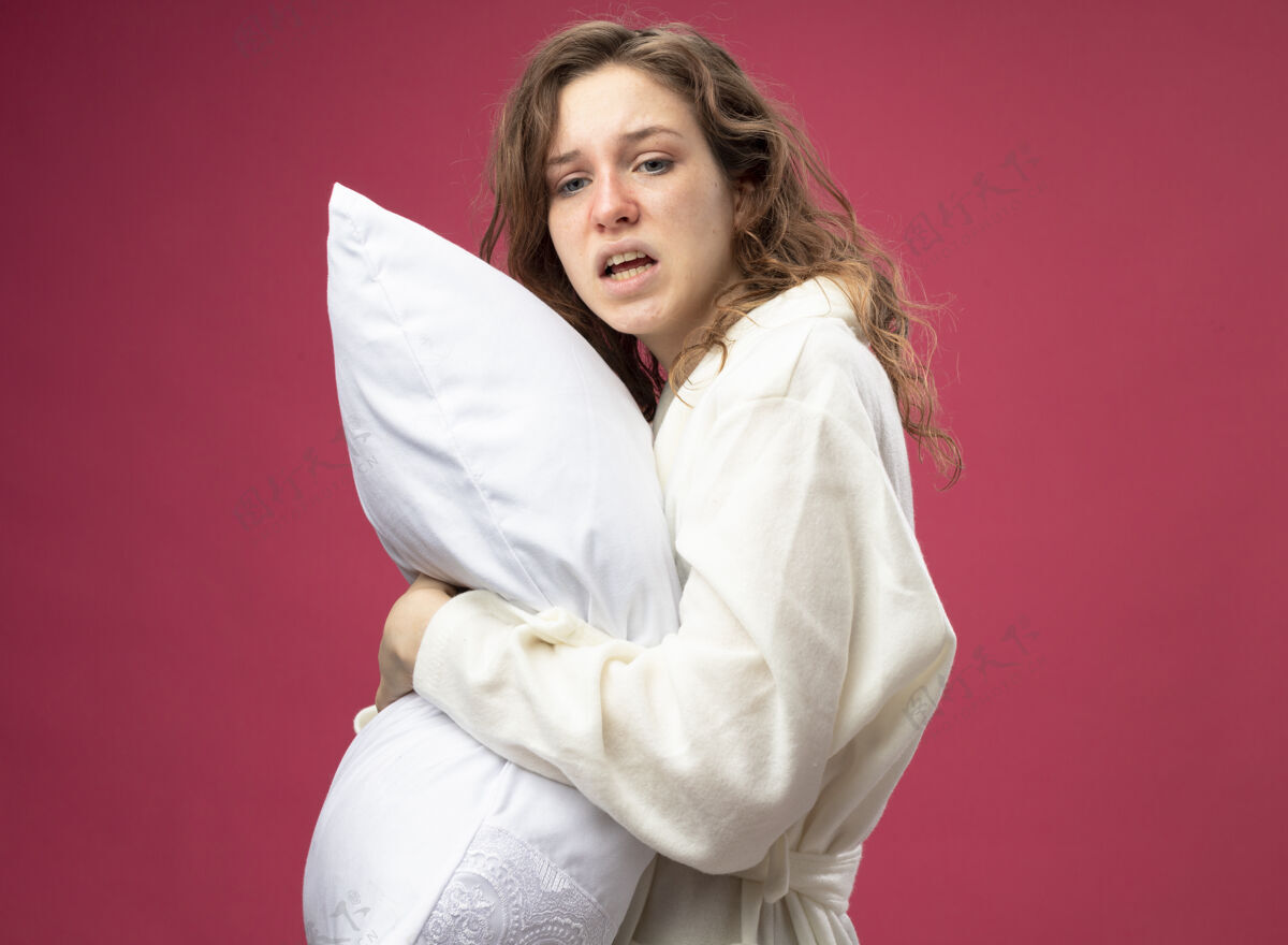 疾病未出柜的年轻病女孩看着身边穿着白色长袍的抱枕孤立地躺在粉红色的床上年轻枕头不愉快