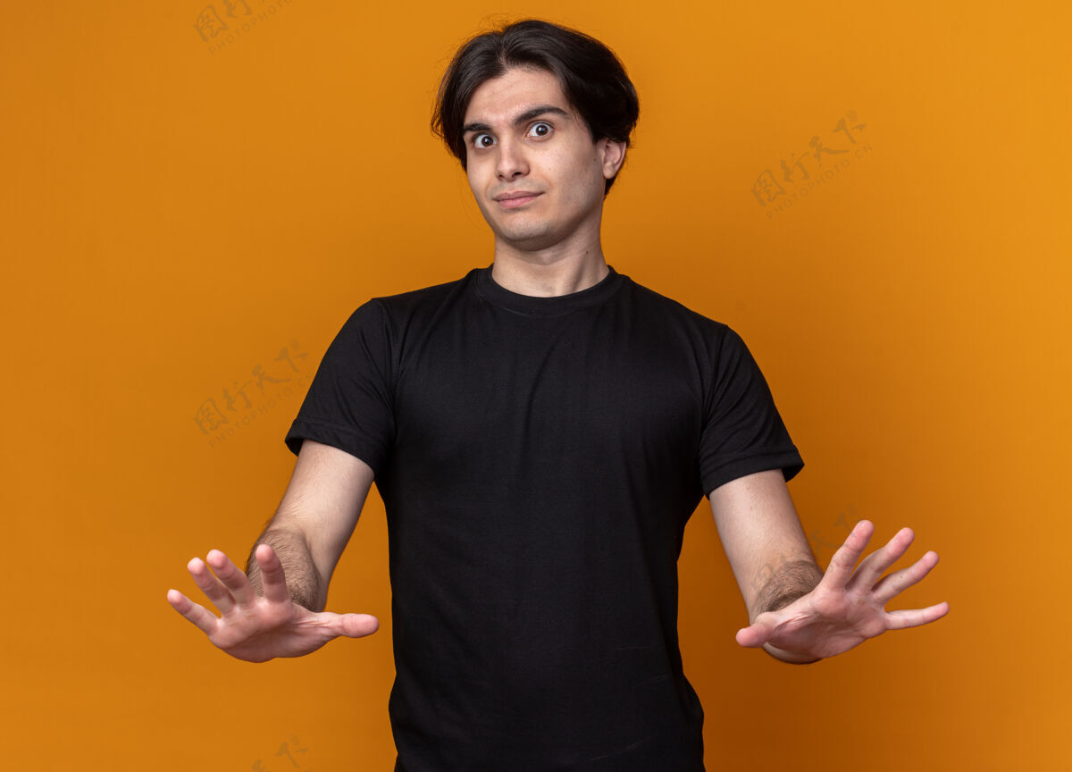 年轻令人印象深刻的年轻帅哥穿着黑色t恤 在橙色的墙上显示停止手势停秀帅哥