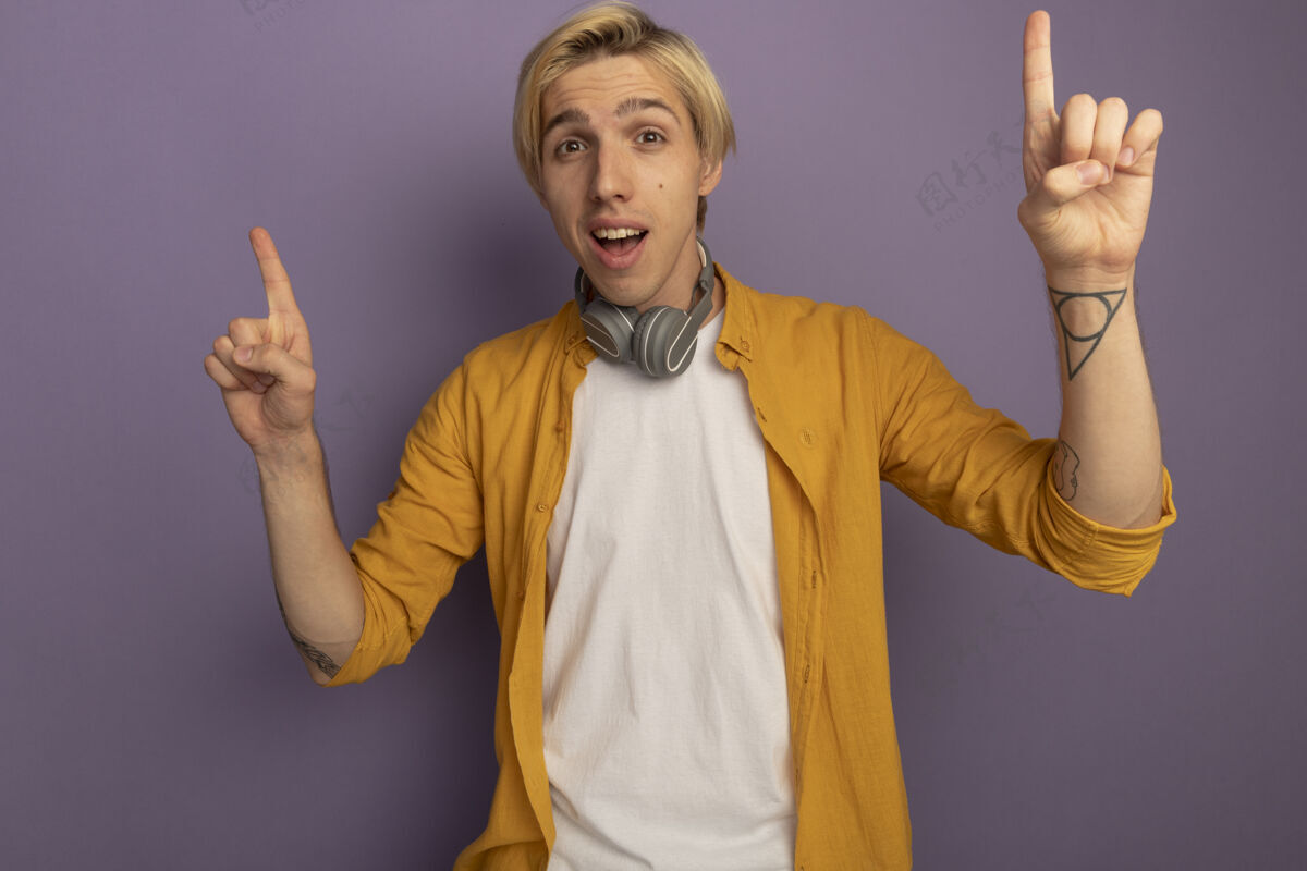 尖令人印象深刻的年轻金发男子穿着黄色t恤和耳机在脖子上点上孤立的紫色印象黄色金发