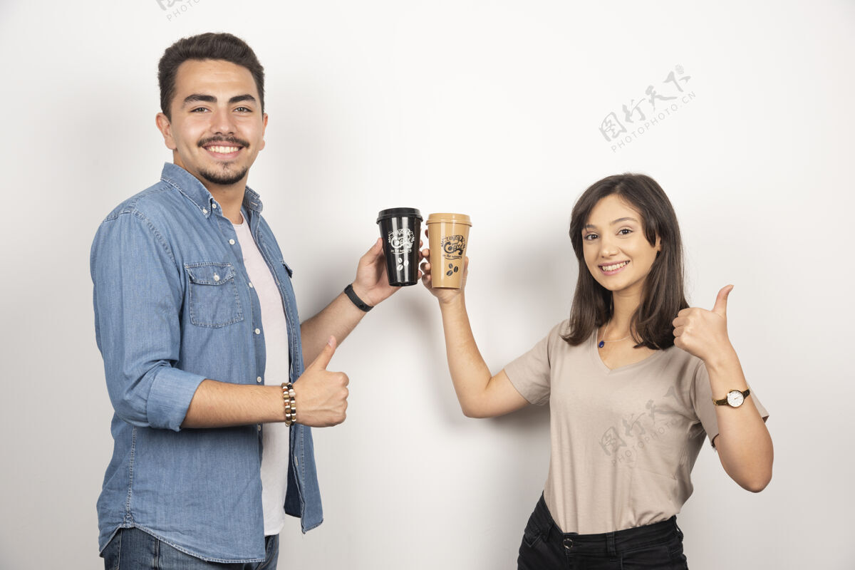 男人微笑的男人和女人端着咖啡 竖起大拇指女人模特人