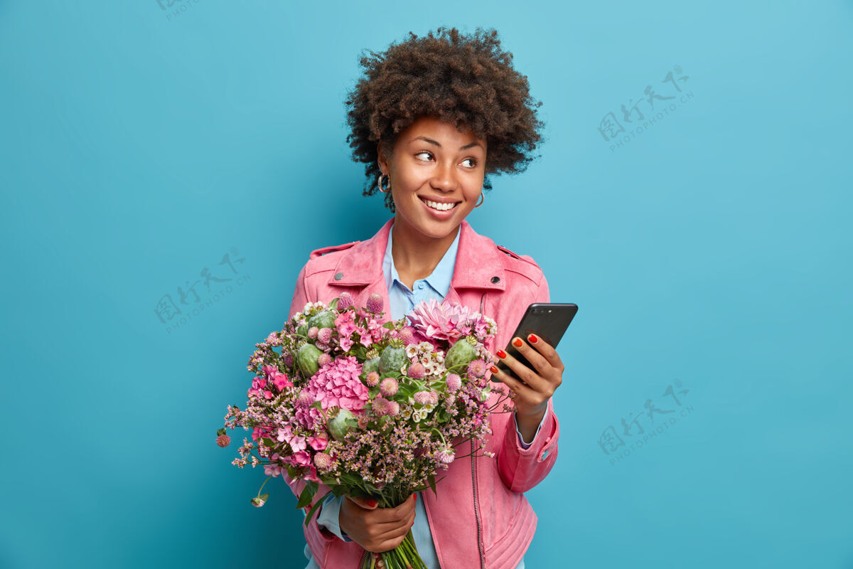 专注漂亮体贴的年轻女子在智能手机上接受祝贺庆祝生日收到漂亮的花束花手机思考