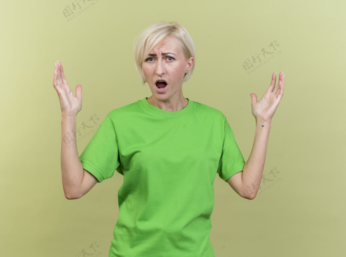 女人愤怒的中年金发斯拉夫女人看着前面 双手在空气中隔离在橄榄绿的墙上斯拉夫人人