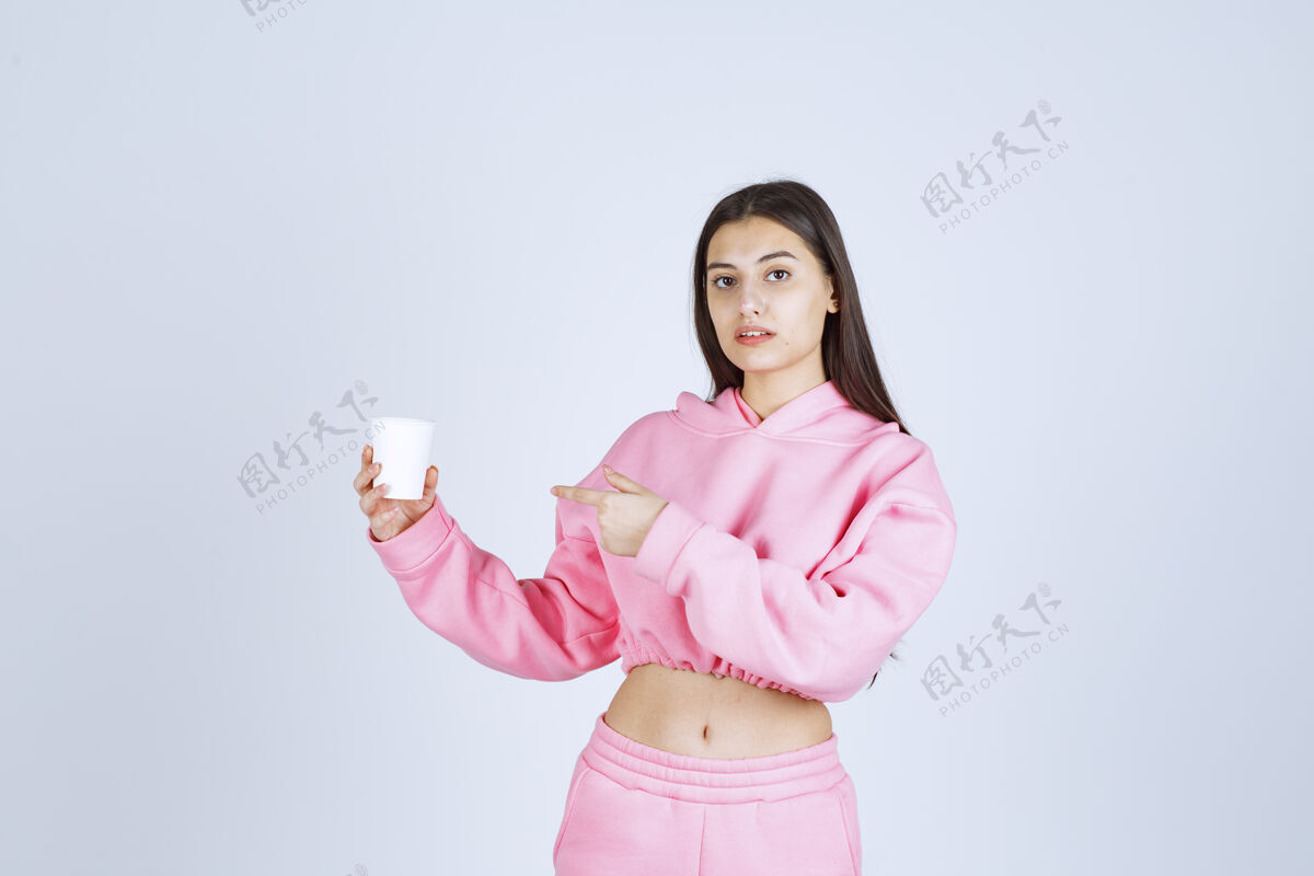 人类穿着粉色睡衣的女孩拿着咖啡杯指着什么东西休息人服装