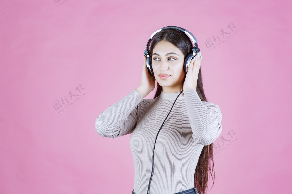 人类戴着耳机的女孩听着音乐 感觉很开心轨道休闲表演