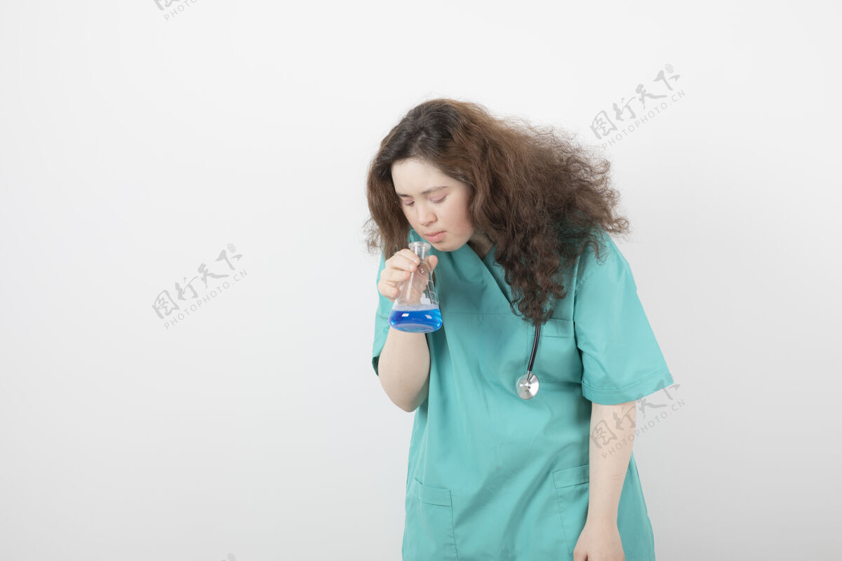 女人一个穿着绿色制服的年轻女孩拿着一个盛着蓝色液体的玻璃罐人女性女孩