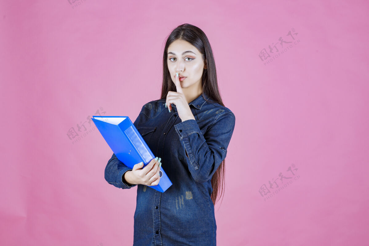 助手女商人拿着一个蓝色文件夹做了一个沉默的标志装备姿势冷静