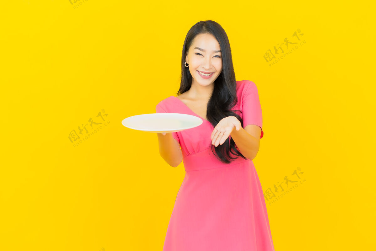 可爱画像美丽的亚洲年轻女子微笑着黄色墙上的空盘子盘子年轻喜悦