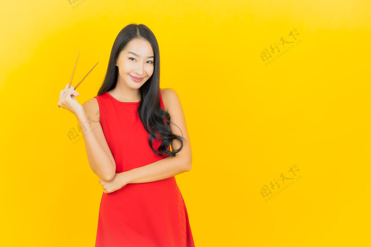 小吃在黄色的墙上画一幅美丽的亚洲年轻女子拿着筷子准备吃饭女人情感一个