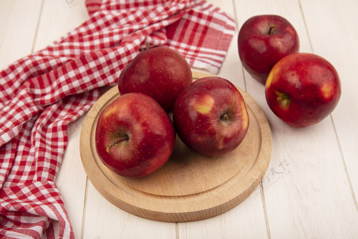 白色白色木质背景上的红色格子布上的木制厨房板上美味的红苹果俯视图木板木头特写