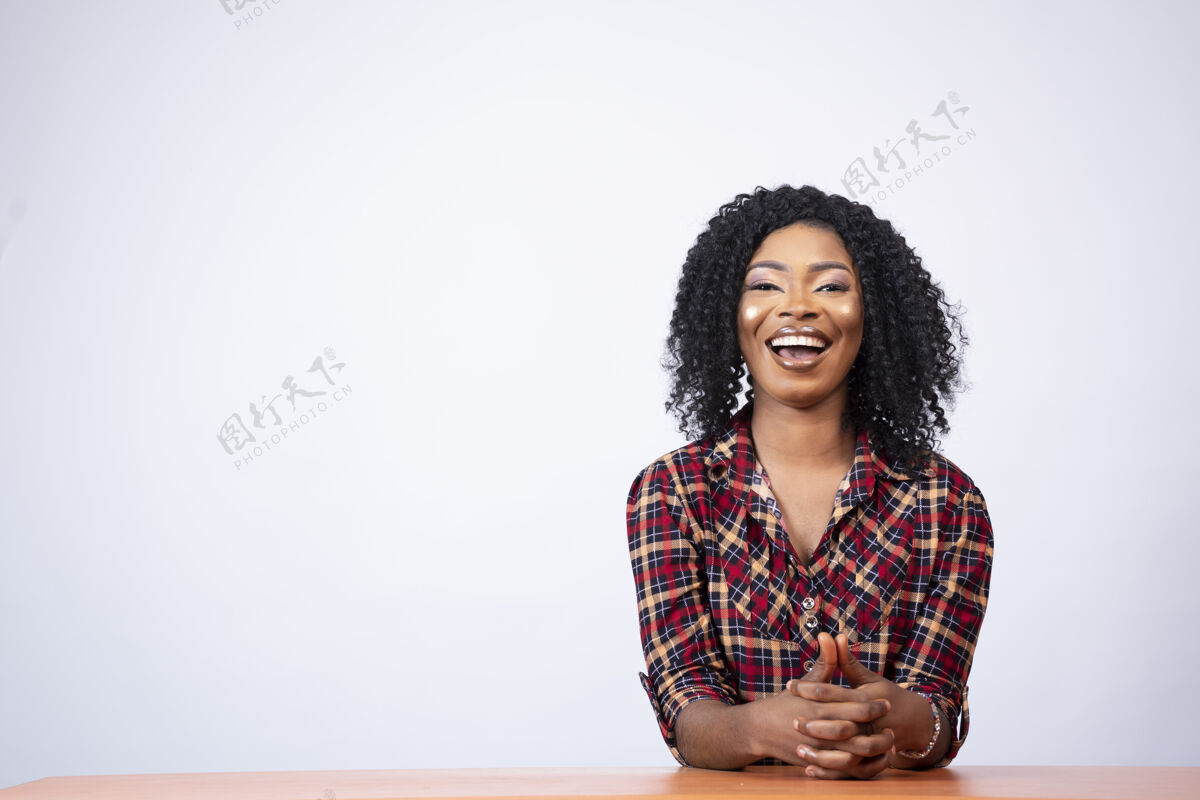 成人坐在书桌旁的一位兴奋的年轻黑人妇女的画像坐着模特漂亮