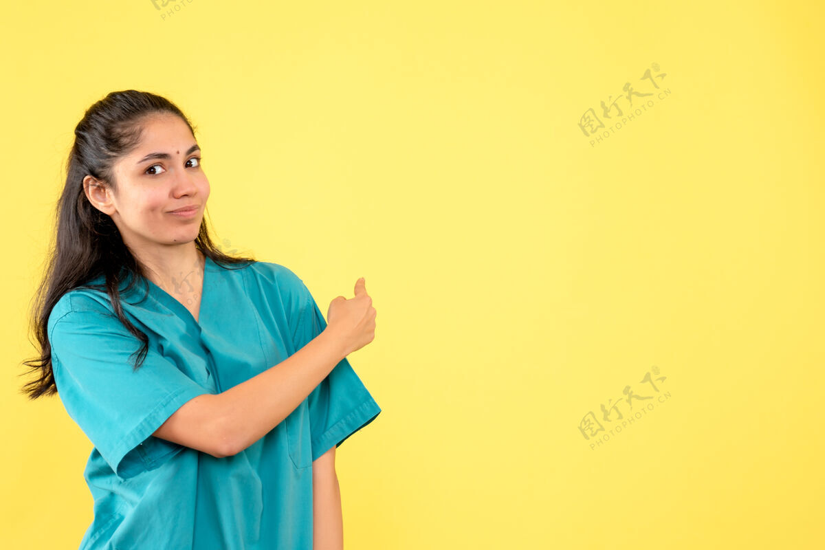 肖像前视图穿着制服的女医生指着后面快乐自信女医生