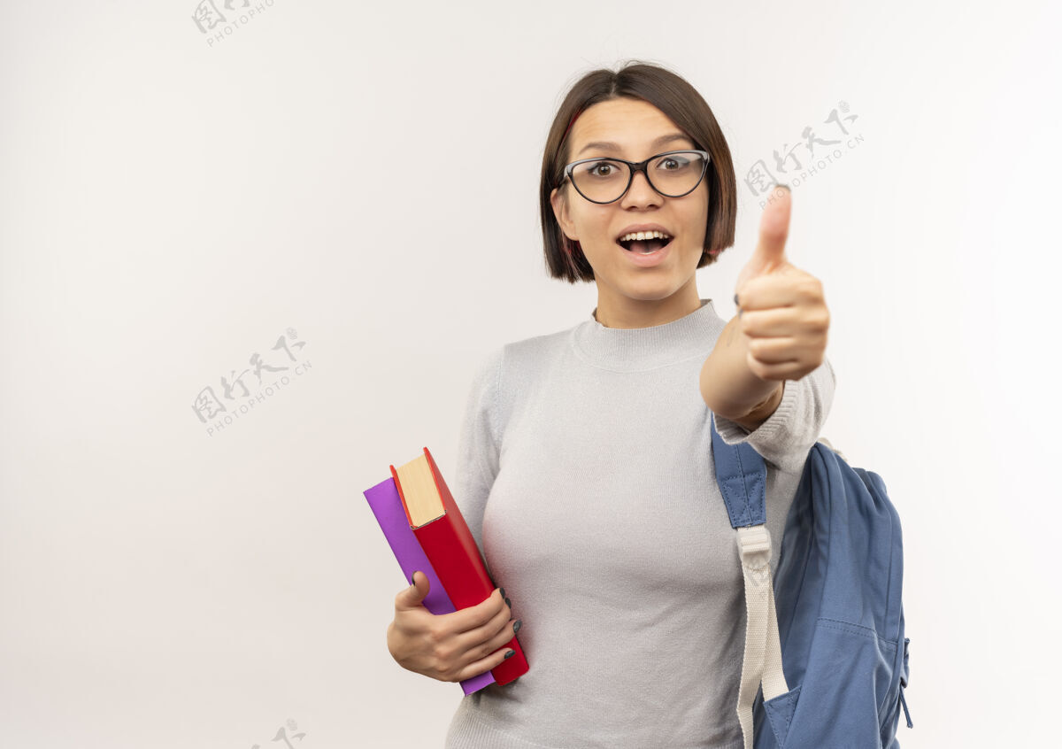 学生给人印象深刻的年轻女学生戴着眼镜 背着书包 在白色的地板上竖起大拇指印象眼镜戴着