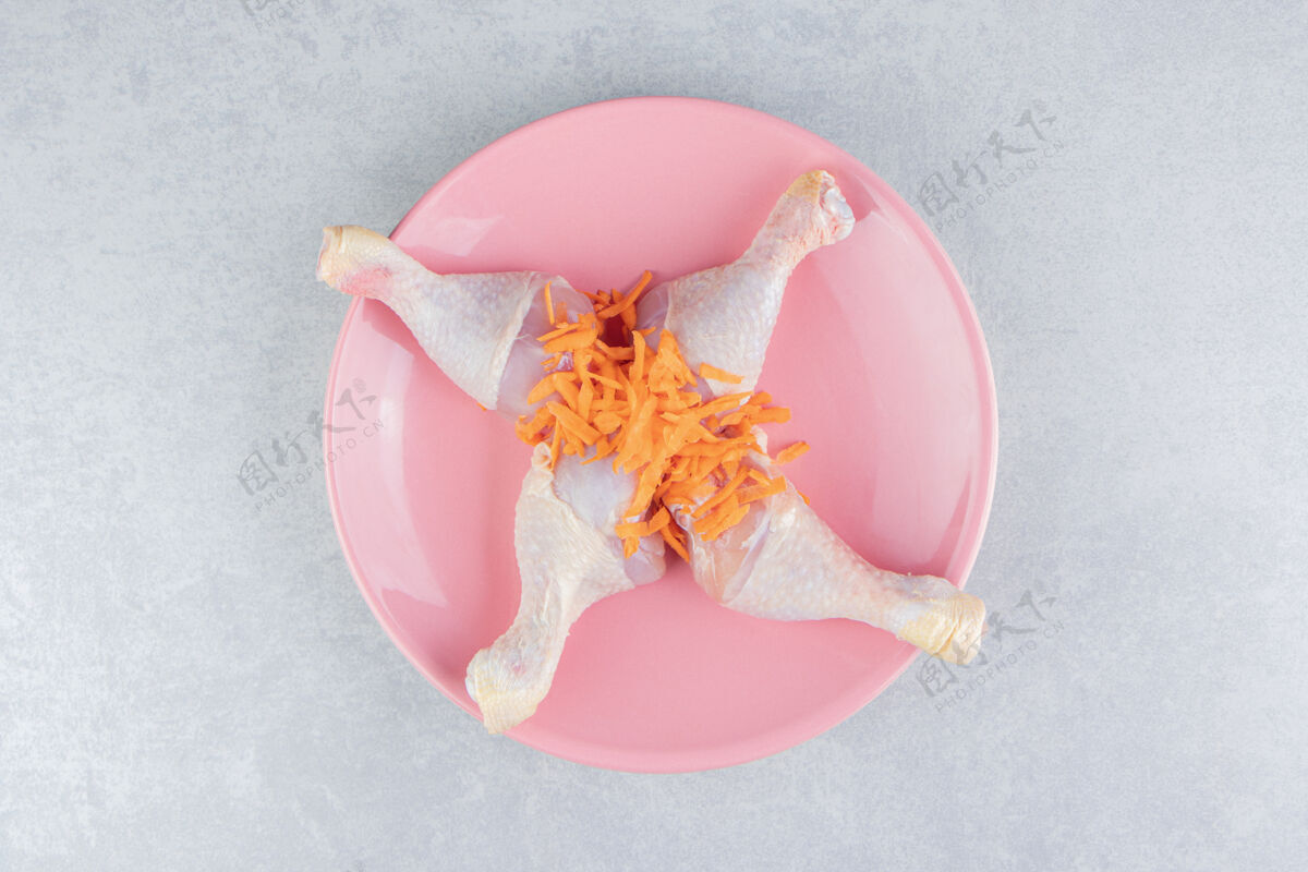 可口把鸡腿和碎胡萝卜放在盘子里 放在大理石表面有机感恩美味
