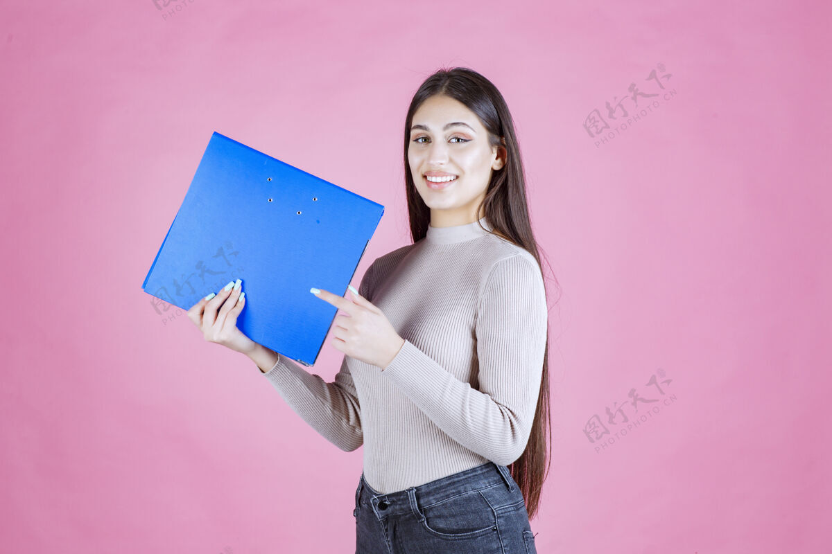 女性女孩拿着一个蓝色的项目文件夹 看起来很成功和快乐报告人女人