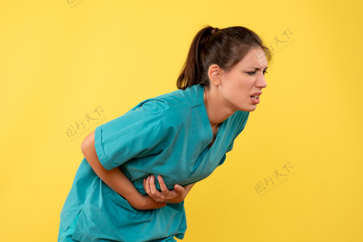 正面正面图黄色背景上穿着胃痛医疗衬衫的女医生护士女医生健康