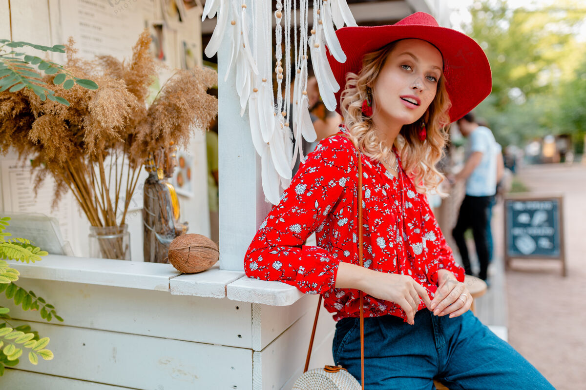 明亮迷人的时尚金发微笑的女人在草编红帽子和衬衫夏季时尚装咖啡厅装束外表优雅