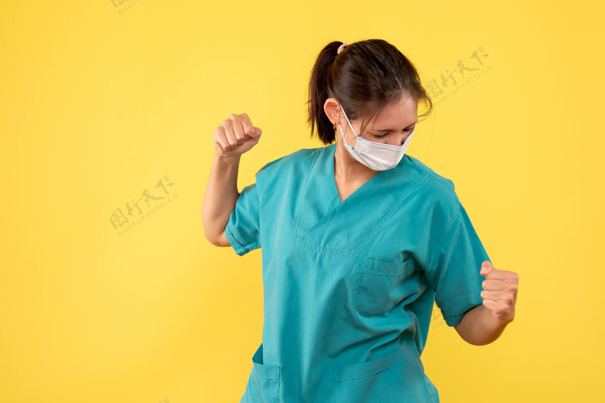 肖像前视图黄色背景上穿着医用衬衫和面罩的女医生成人人视图