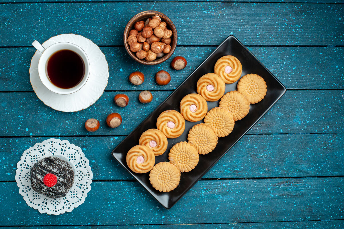 咖啡俯瞰一杯茶 配上坚果和饼干 放在乡村的蓝色桌子上 糖饼干 甜甜的饼干蛋糕坚果顶部咖啡因