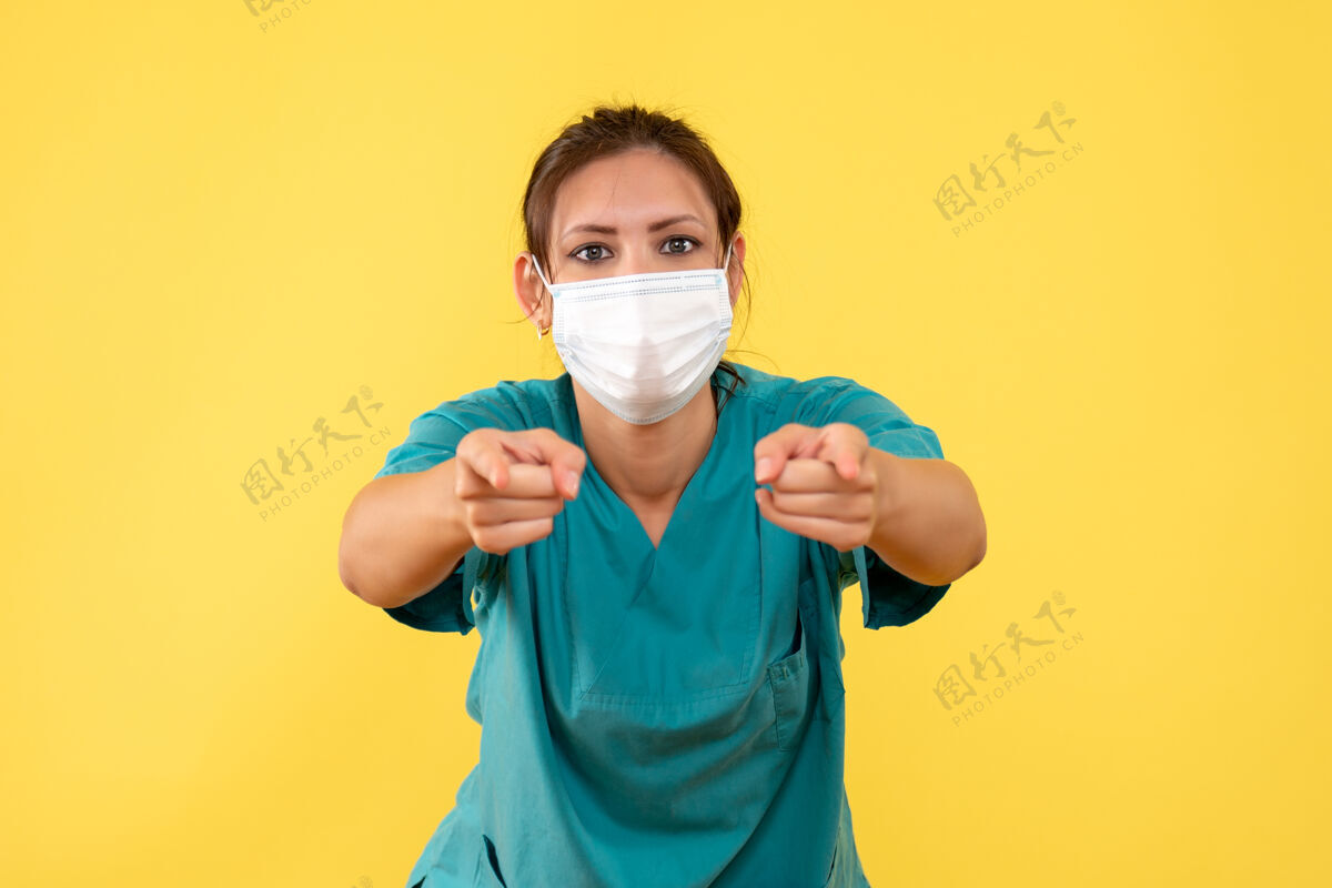 肖像前视图黄色背景上穿着医用衬衫和面罩的女医生视图成人脸