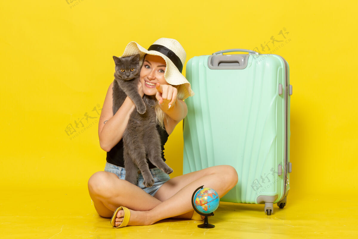 年轻正面图年轻的女性坐在黄色的墙上拥抱小猫旅行度假航海旅行太阳海漂亮风景