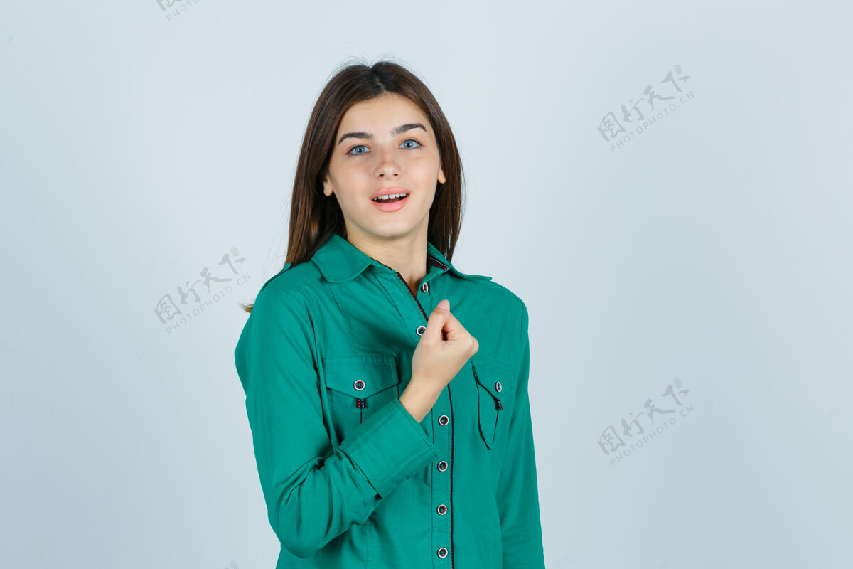 胸部穿着绿色上衣的年轻女孩握紧拳头放在胸前 看上去很欢快正面视图年轻衬衫年轻