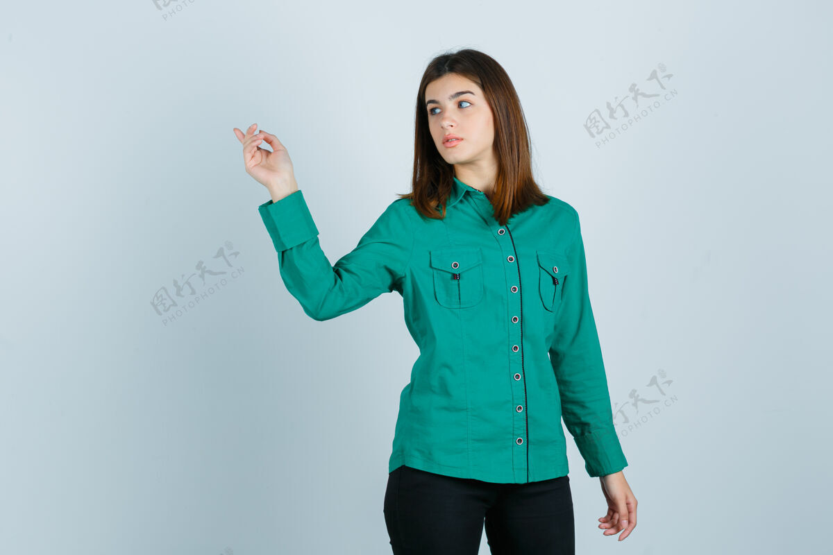 鞋面穿着绿色衬衫的年轻女性 裤子指向左上角 看起来很专注 正面视图使用电话女性