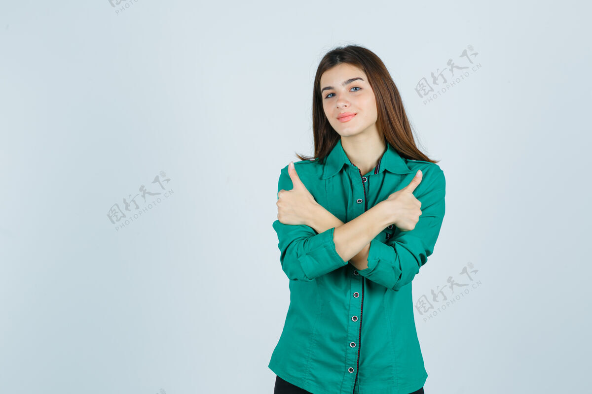 表演一幅美丽的年轻女士的肖像 她穿着绿色衬衫 向上竖起大拇指 看上去很欢快正面成人微笑