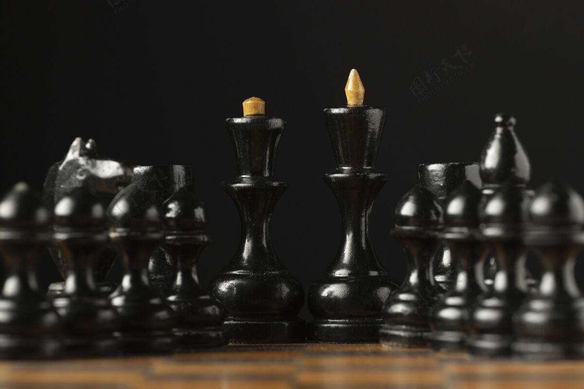 棋盘棋盘上的黑色棋子国王和王后棋子小雕像黑色背景黑色