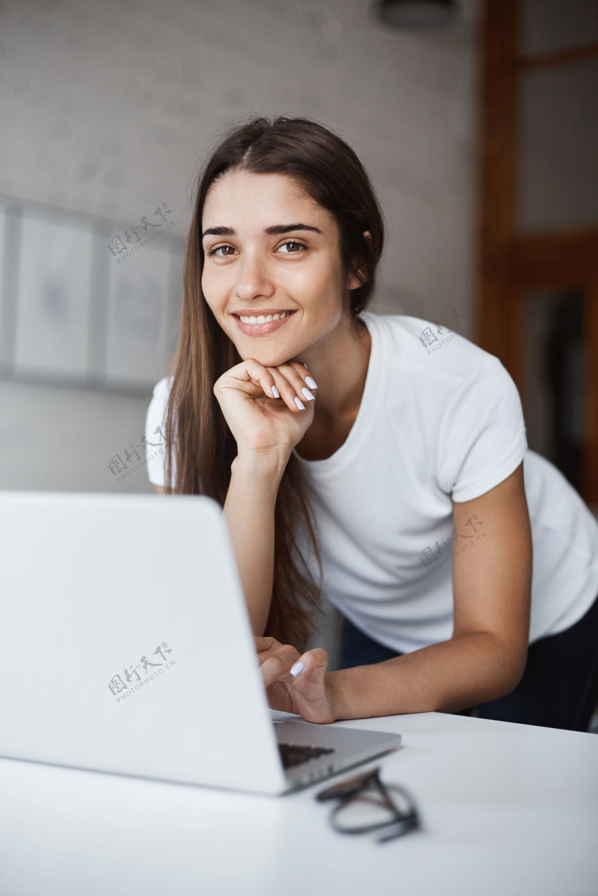 时尚美丽的高加索女孩用笔记本电脑看猫视频在网上看着相机微笑设计师人电话