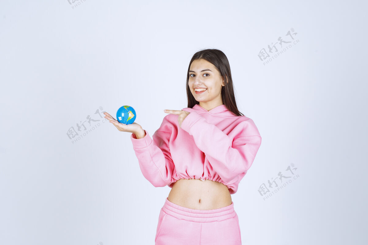 人体模型穿着粉色睡衣的女孩拿着一个迷你地球仪指着它姿势人职员