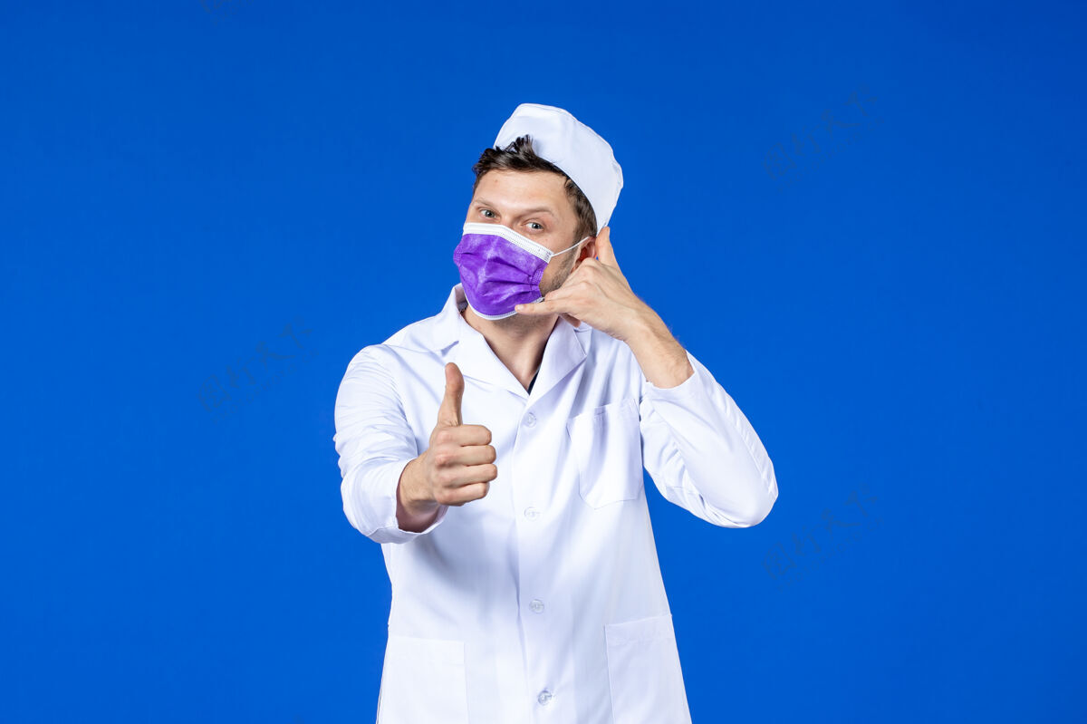 男医生身穿医疗服 戴着紫色口罩的男医生在蓝色屏幕上模拟打电话大流行医院病毒