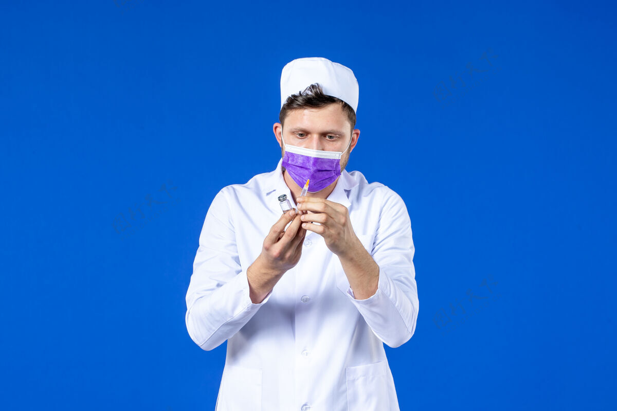 疫苗男医生的前视图 穿着医疗服 戴着蓝色的注射和疫苗面罩男医生病毒药品