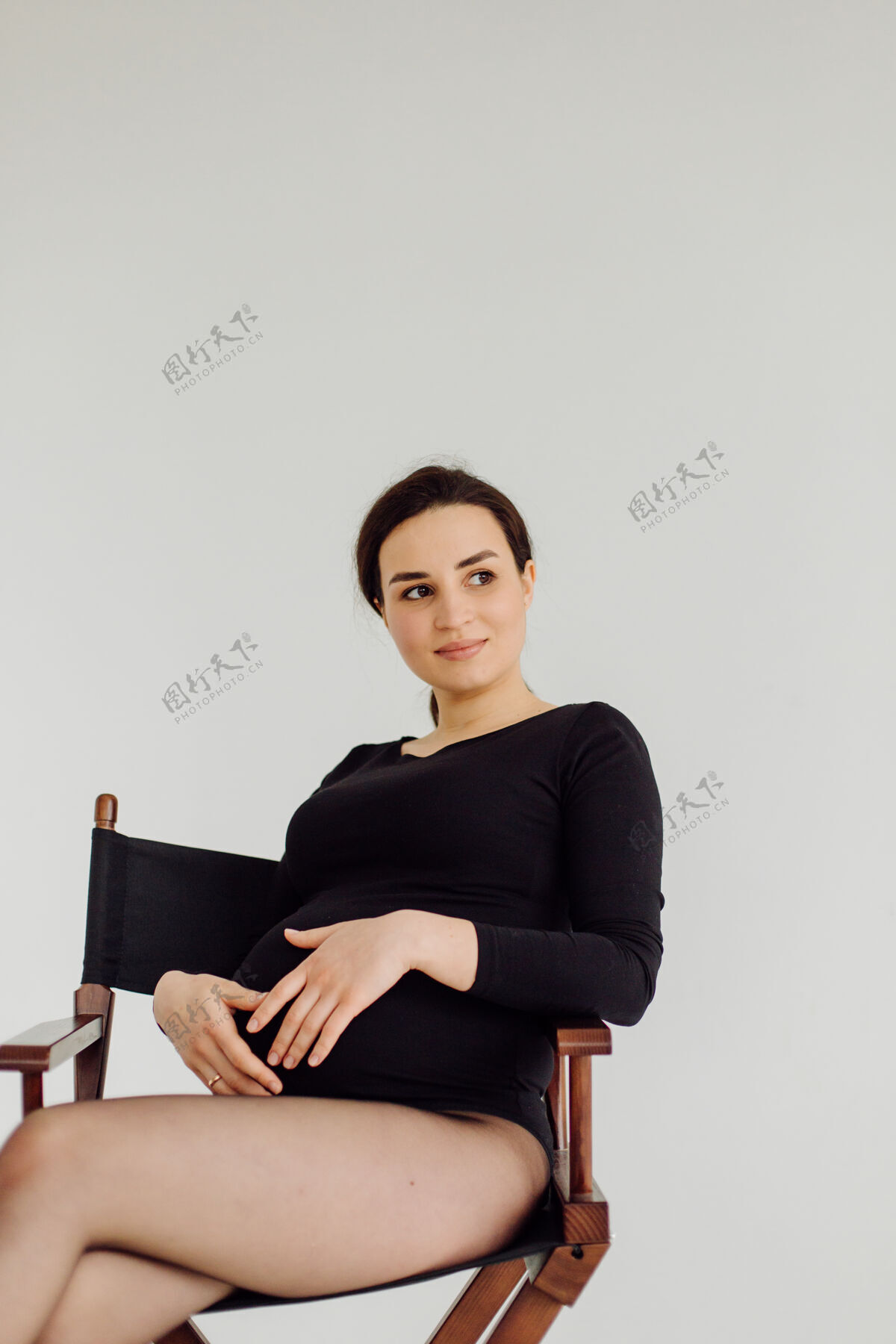 怀孕美丽的年轻孕妇穿着礼服在摄影棚摆姿势化妆女性腹部