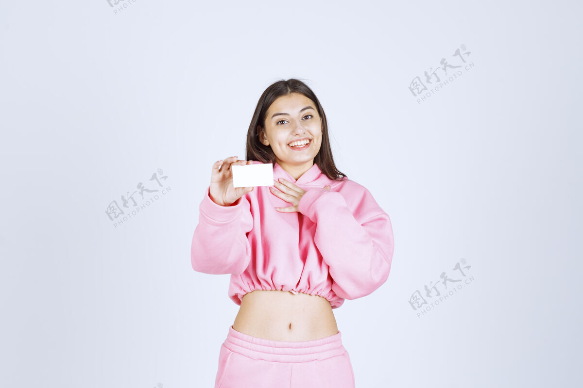 休闲穿着粉色睡衣的女孩拿着名片指着自己模特人类女性