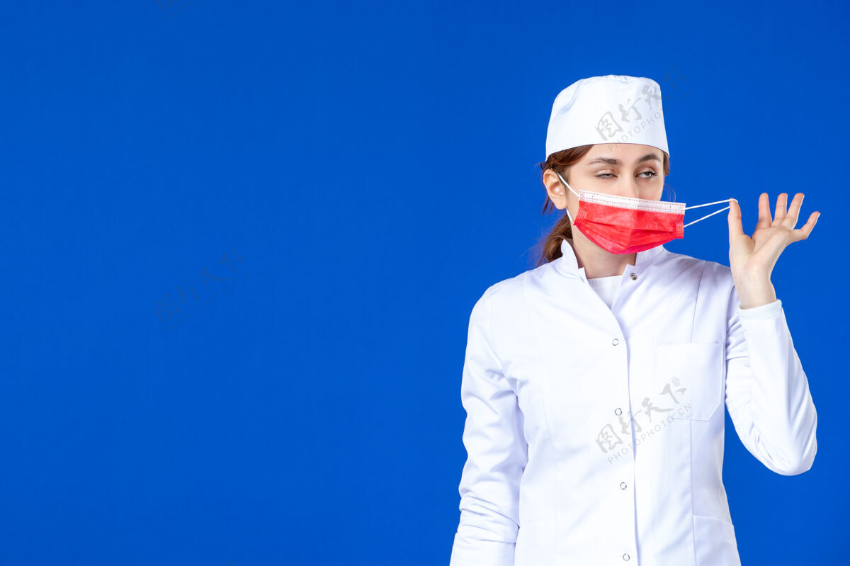 流行病身穿医疗服的年轻护士的正视图 蓝色的面具上有红色的面具病毒年轻护士衣服