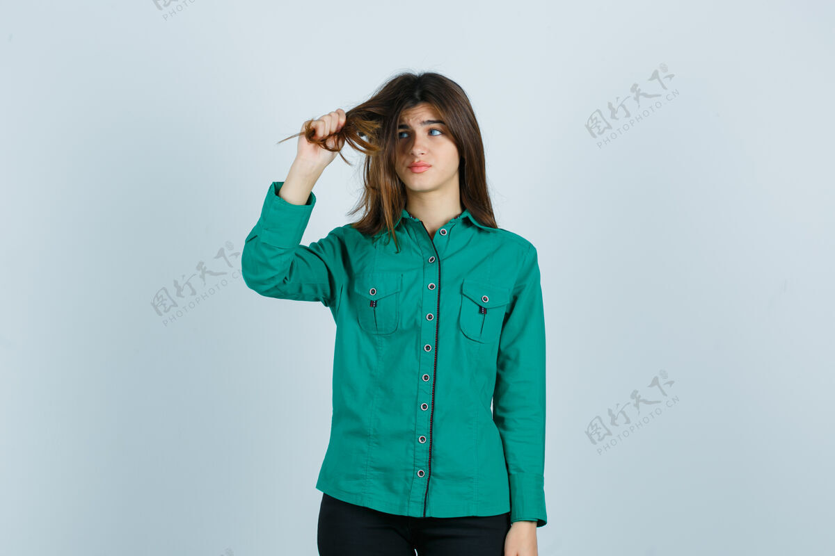女士一位年轻的女性 穿着绿色衬衫 拉着她的头发 看起来很失望 正面视图黑发人年轻