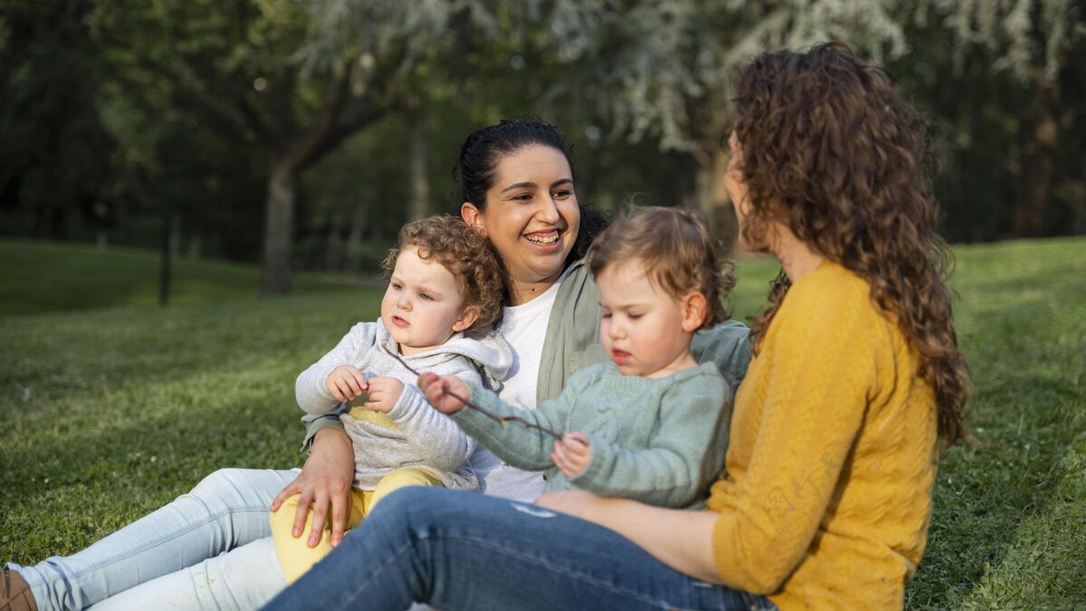 女人公园外lgbt母亲和孩子在草地上放松的侧视图女同性恋公园夫妇