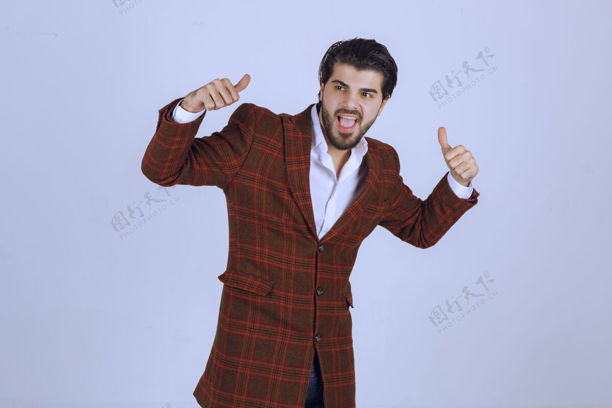 模特穿棕色西装的男人在做竖起大拇指的招牌积极聪明成功