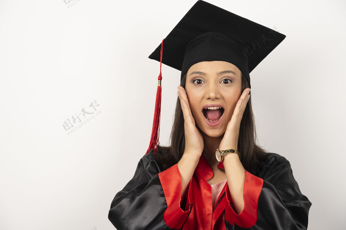 成功在白色背景上 应届毕业生用惊讶的表情捂住耳朵帽子长袍教育