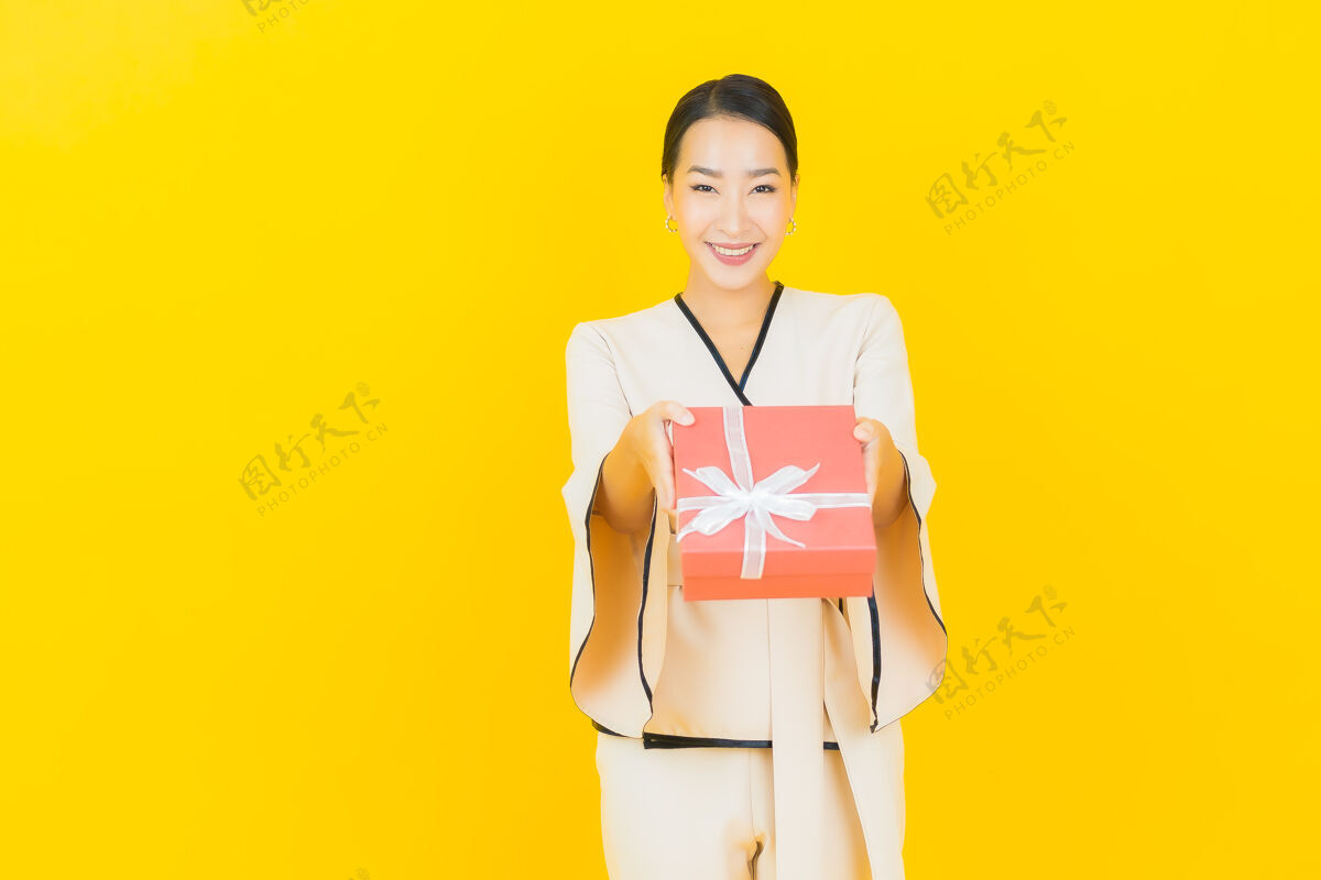 美丽黄墙上挂着红色礼盒的亚洲商界年轻美女画像美女欢呼亚洲