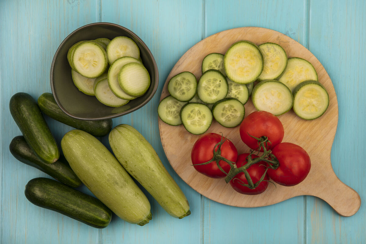 农业健康蔬菜的俯视图 如西红柿 切碎的黄瓜和西葫芦 放在木制厨房板上 黄瓜和西葫芦被隔离在蓝色的木制表面上西葫芦配料饮食
